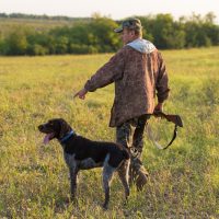 Hunter man in camouflage with a gun during the hunt in search of wild birds or game. Autumn hunting season.